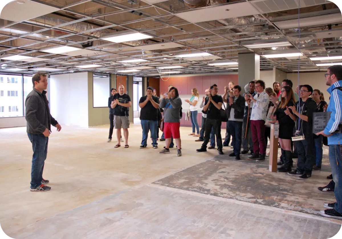 Unfinished office with a group of people paying attention to a single man