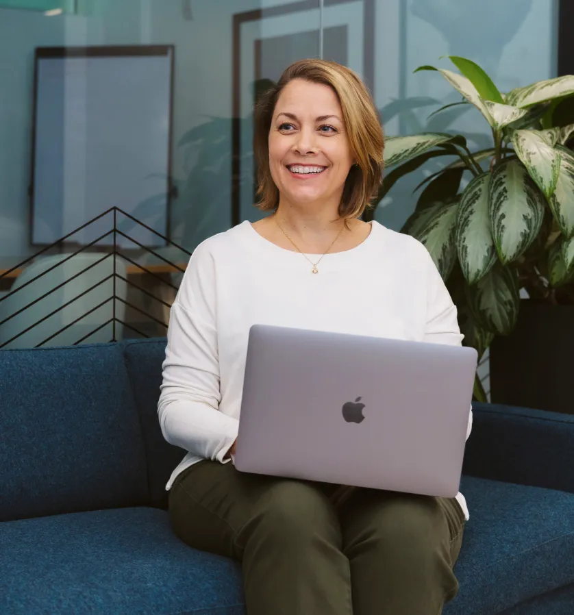 Blonde woman in office with laptop smiling